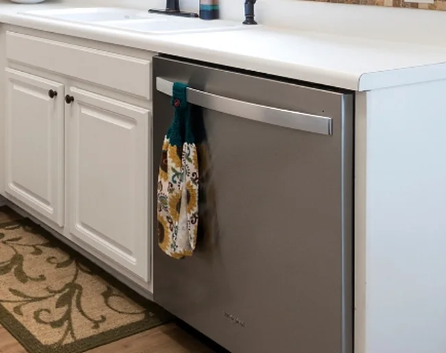 A stainless dishwasher built into white kitchen cabinets