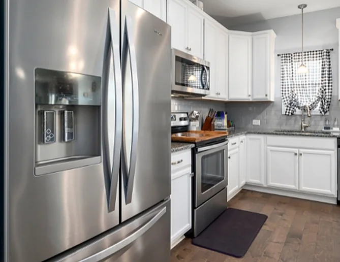 A bright kitchen with a stainless refrigerator, range and microwave