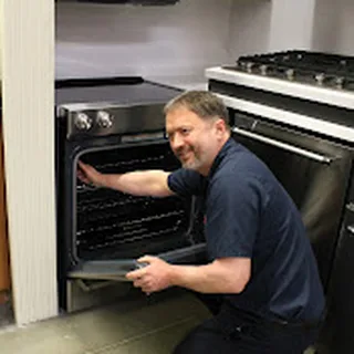 An Appliance Master technician repairing an oven in a customer's kitchen